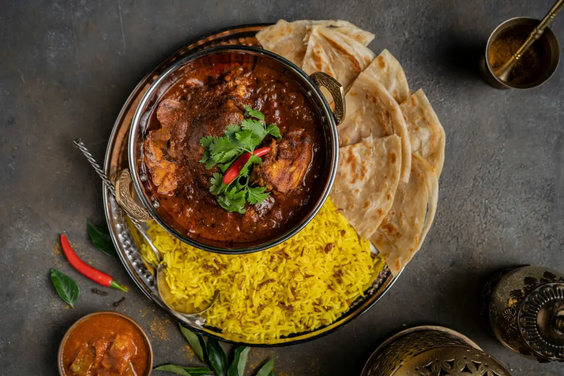 a bowl of curry, rice and pita bread